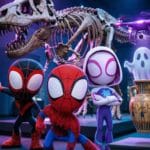 Dibujo de Spidey, Gwen y Miles descubriendo a un pequeño dron morado que proyecta un fantasma flotante en el museo, estilo animación 3D.