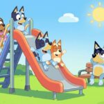 Bluey y Bingo deslizándose felices por el tobogán del parque con sus amigos mientras sus padres observan.